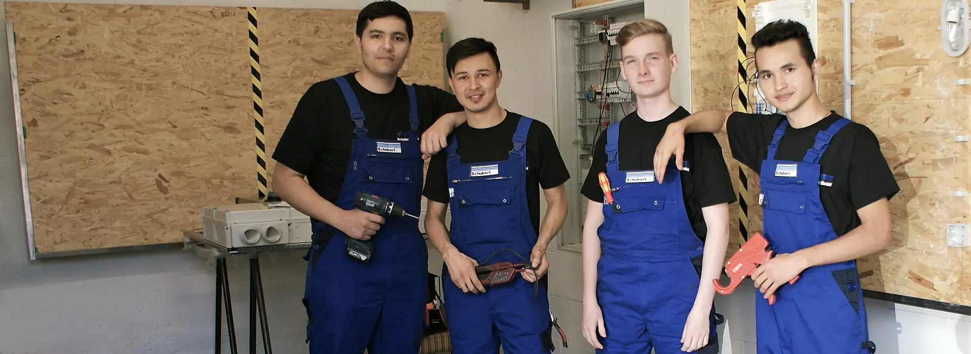 Four young workers in blue overalls